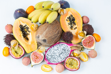 assorted exotic fruits on a white background: coconut, bananas, passion fruit, papaya, pitahaya