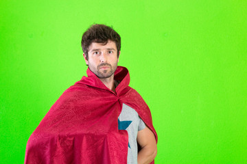 Young crazy super hero serious expression, confused and doubtful on green background
