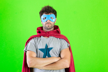 Young crazy super hero serious expression, confused and doubtful on green background