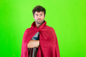 Young crazy super hero serious expression, confused and doubtful on green background