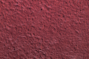 The textural surface of the wall of a house of the fashionable color Baking red lit by the sun .