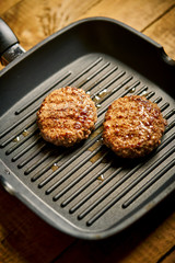 Closeup of juicy burgers fried on black grill pan