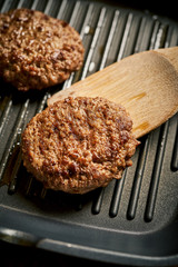 Closeup of juicy burgers fried on black grill pan