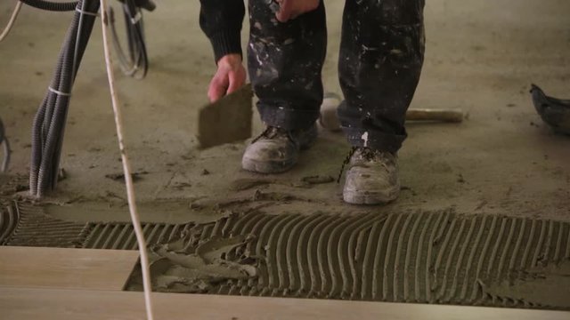 Construction Worker Putting On New Wood Flooring Using Adhesive