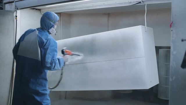 Metal powder coating. Professional hand spray painting of a metal products. Worker at factory painting metal details with a gun of powder coating