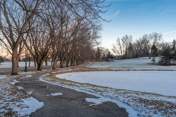 Winter View in Neighborhood with Bare Trees on the Sides and Frozen Pool