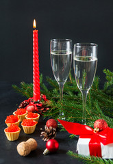 glasses of champagne, wine sparkling, red candle, tartlets with red caviar, gift box with red ribbon , fir  on a black