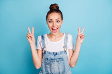 Portrait of cheerful girl screaming making v-signs wearing white t-shirt denim jeans overall...