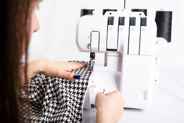 Naklejka premium Overlock. The woman sews the knit fabric on the overlock
