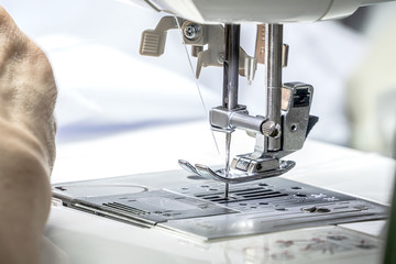 The seamstress is using the sewing machine.