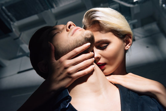 low angle view of attractive woman with red lips hugging man