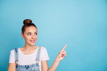 Portrait of attractive girl looking at ads wearing white t-shirt denim jeans overalls isolated over blue background