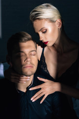 attractive woman in black underwear hugging handsome man in shirt with closed eyes