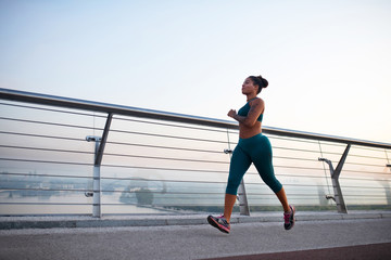 Dark-skinned woman wearing leggings enjoying morning run