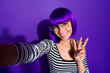 Close up photo of charming girl making photo v-sign smiling isolated over purple violet background