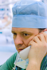 Young doctor with phone in ICU