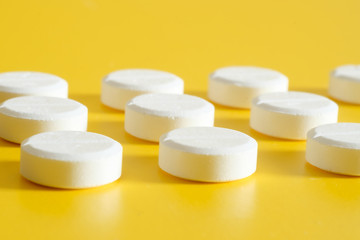 Fototapeta na wymiar White medication pills arrangement on yellow background