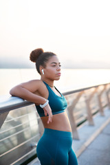 Woman wearing smart watch and earrings standing on bridge