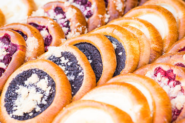 Sweet round cakes (Czech: kolace) with cream cheese, poppy seed, plums, strawberries or forest fruit filling.  Closeup image of tasty bakery products on traditional autumn market stand.