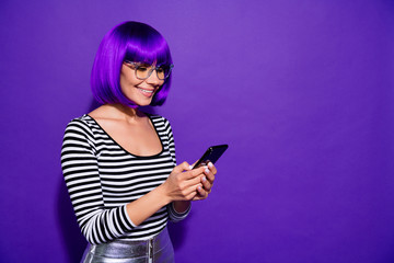 Portrait of charming youngster using modern technology reading news isolated over purple violet...