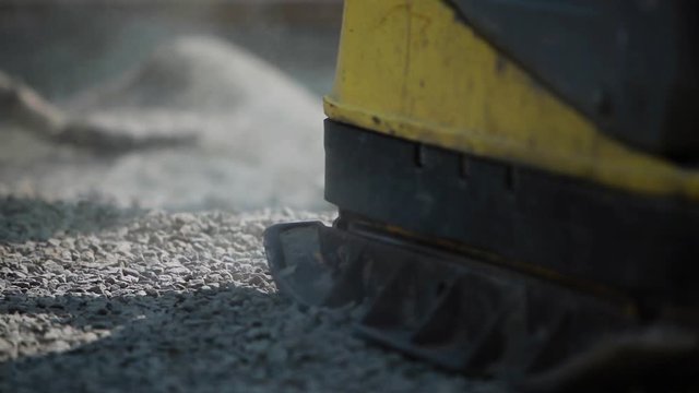 Stone Pavement Road Construction Workers. Leveling The Sand Layer with a finishing plate compactor