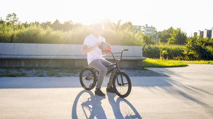 Portrait of young BMX rider with cap getting ready on BMX bike in a park
