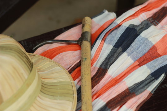 flat lay details showing the tools and colorful clothing and bamboo woven hat of a traditional Northern Thailand Thai Elephant Mahoot trainer, Southeast Asia