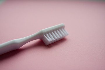 White toothbrush used for cleaning the teeth on pink background