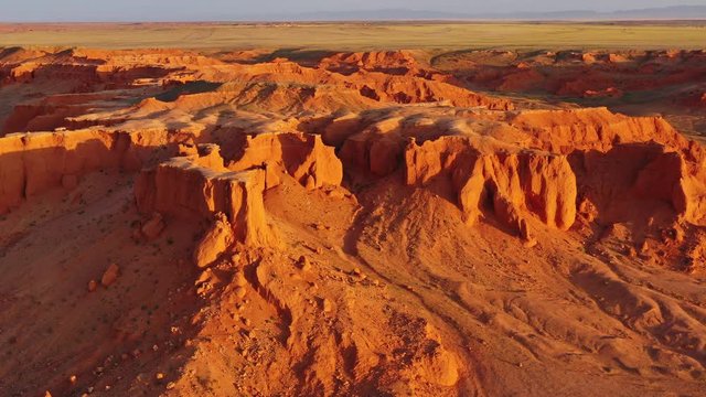 Aerial around view of the Bayanzag flaming cliffs at sunset in Mongolia, found in the Gobi Desert, 4k