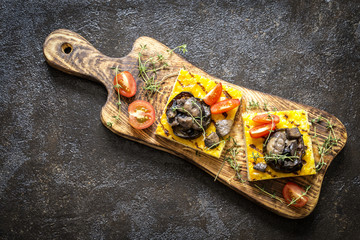 polenta corn with fried eggplant and mushrooms and cherry tomatoes on a dark background