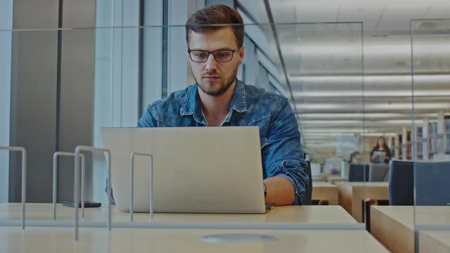 Young man working on a laptop in public library
