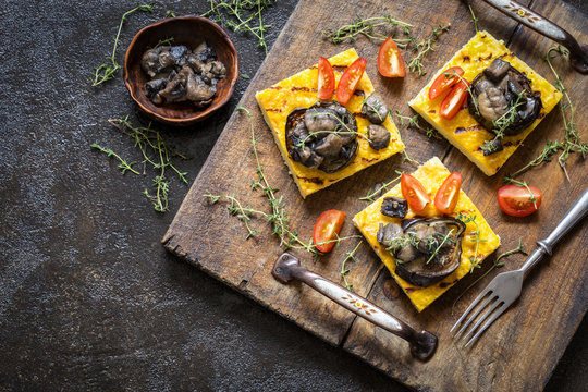 polenta corn with fried eggplant and mushrooms and cherry tomatoes on a dark background