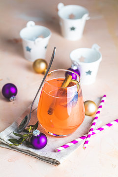 Christmas and New Year pink cocktail with fig and cinnamon  in glass on pink concrete background, close up, surrounded  holiday decor. Winter festive drinks and alcoholic cocktails or detox drink