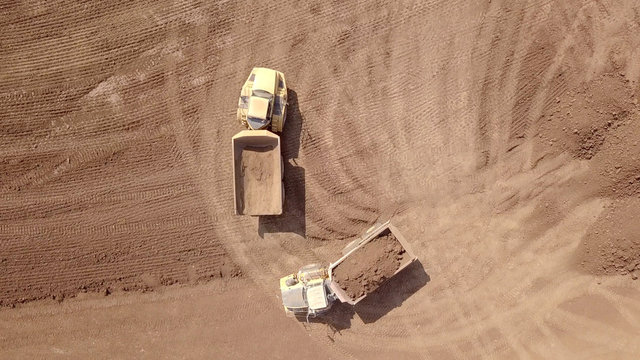 Aerial image of Two Truck one loaded with Soil and one empty at an industrial development site.