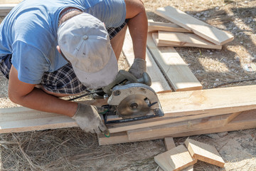 A worker cuts a wooden board at a construction site