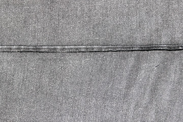 Texture of the inner side of a black denim fabric with the black overstitch