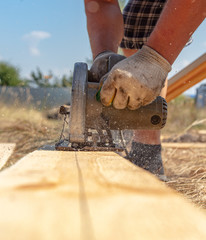 A worker cuts a wooden board at a construction site