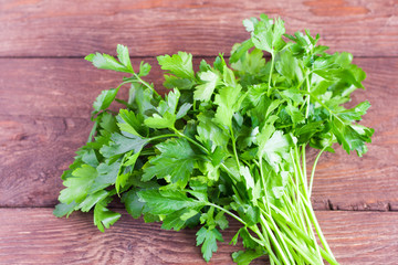 Bunch of fresh parsley on the background of a wooden table. Fresh parsley on a wooden background. Parsley closeup on a village Board