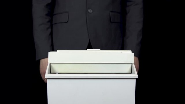 Schroeder destroys one hundred dollar bill. Businessman in a suit thrusts money into a paper shredder