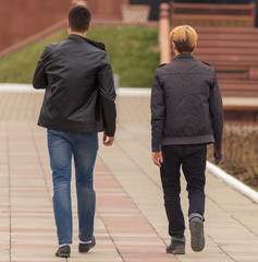 Two men are walking along the road in the park