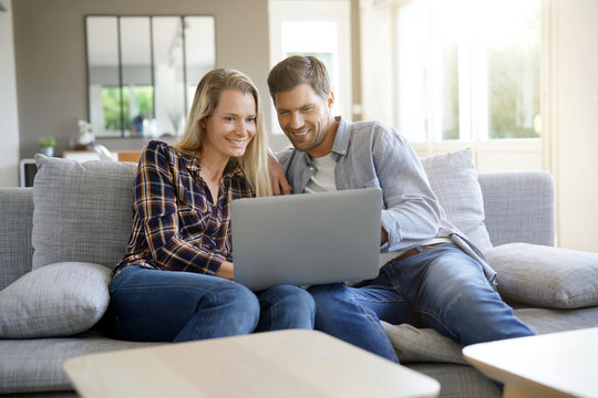 Cheerful Couple At Home Using Laptop