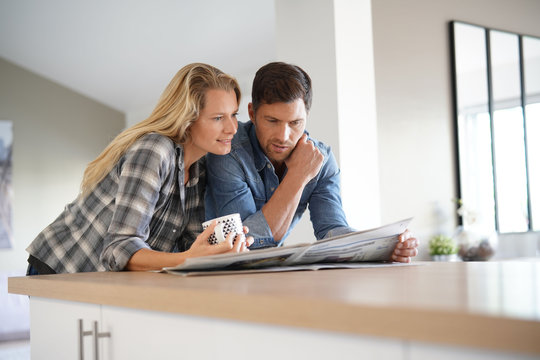 Couple at home reading newspaper