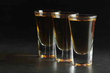 Three shots with whiskey at dark background