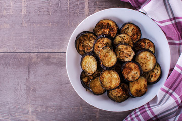 fried eggplant on the plate on rustic wooden background - top view. copyspase
