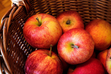 Fresh harvest of apples. Nature theme with red grapes and basket on wooden background. Nature fruit concept.