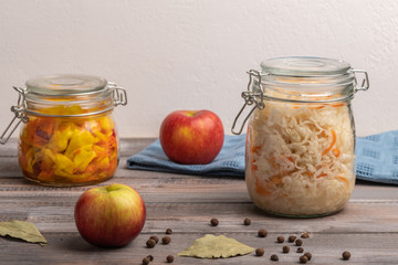 Homemade canned cabbage with apples in jars with bay leaves on a wooden table. Rustic style