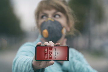 Woman wearing a real anti-smog face mask and checking current air pollution with smart phone app