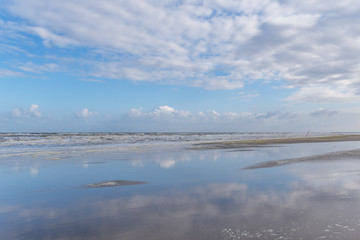 Obraz na płótnie Canvas Morgenstimmung am Meer - Wolken spiegeln sich im Wasser am Strand - Kijkduin Strand, Den Haag, Holland, Niederlande