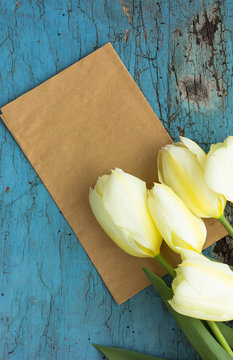 White tulips on blue background with frame, flower postcard for Women's Day, Mother's Day or sale concept. Floral spring background with copy space.
