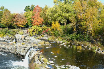 Vibrant orange, yellow, red and green fall colors on trees near waterfall